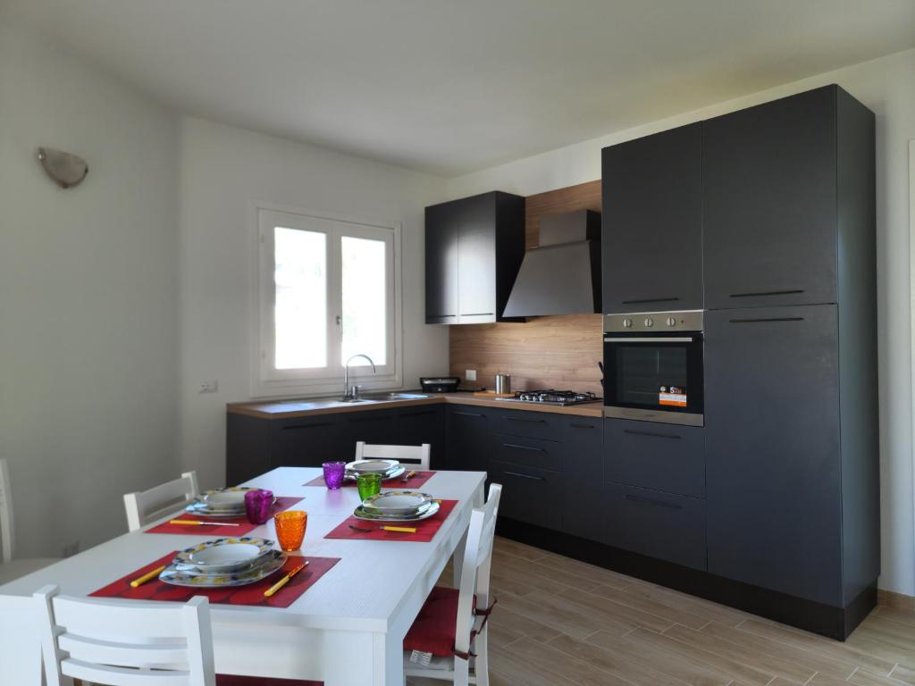 une cuisine avec une table blanche avec des chaises blanches et une cuisine avec des armoires noires dans l'établissement Villa Lu Tizzoni, à Budoni 17 autres photos