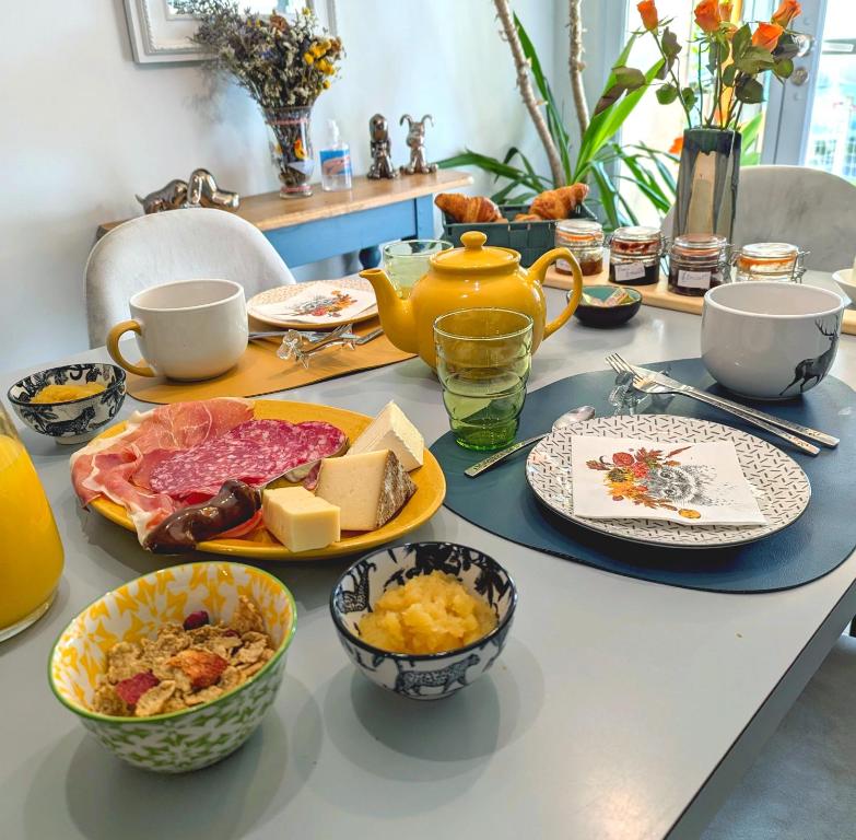 uma mesa coberta com pratos e tigelas de comida em Chez Nick et Martine suite privative em Palinges