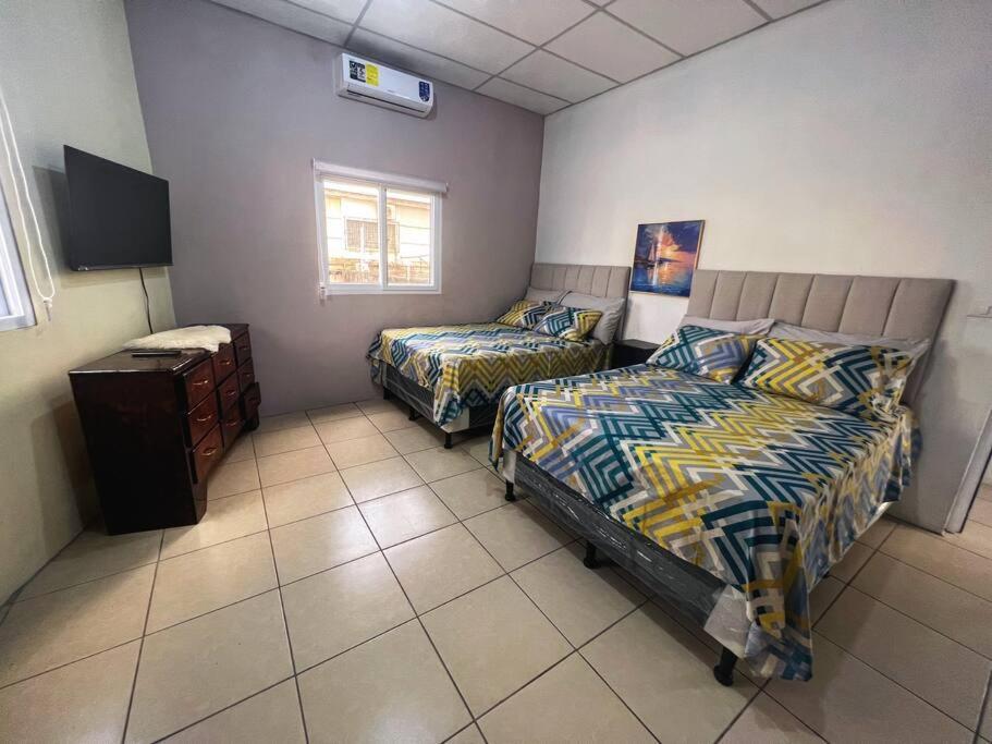 a bedroom with two beds and a tv in it at Departamento Centrico, cerca de todos los balnearos de Puerto Barrios in Puerto Barrios