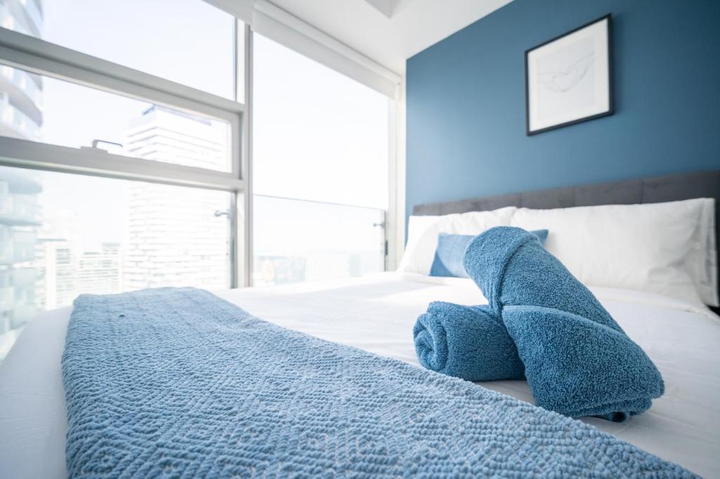 a blue stuffed animal sitting on top of a bed at Downtown Apartments (5) in Toronto