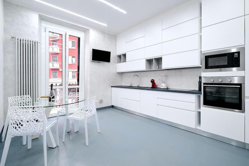 uma cozinha com armários brancos e uma mesa e cadeiras em Suite Milano-Hosted by Sweetstay em Milão