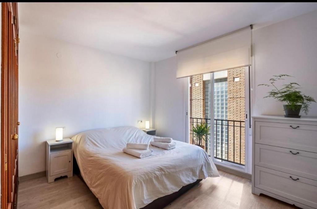 Habitación blanca con cama y ventana en Casa con piscina y chimenea en Albayzin alto en Granada