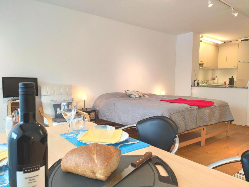 Cette chambre comprend une table avec une bouteille de vin et un lit. dans l'établissement Studio Haus Arabelle by Interhome, à Davos