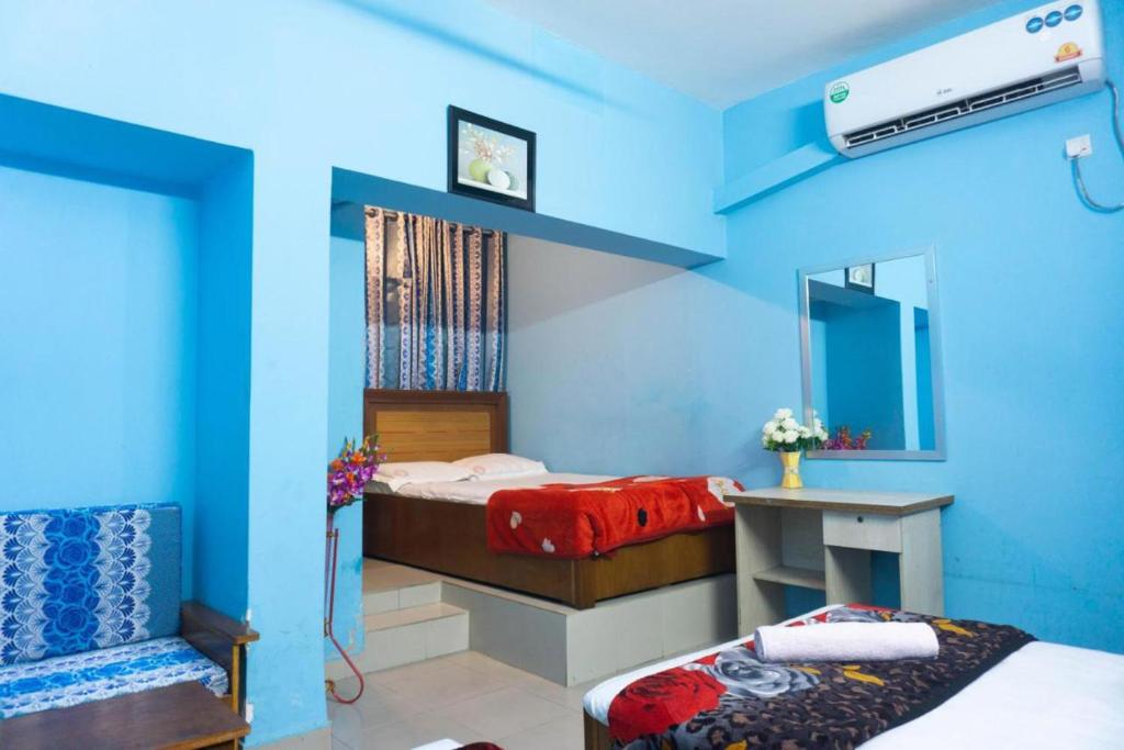 a blue room with two beds and a table at Hotel Panthapath Dhaka in Dhaka