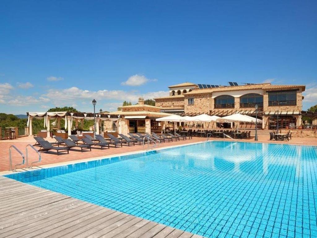 een groot zwembad met stoelen en een gebouw bij Apartment Hapimag-1 by Interhome in Platja  d'Aro