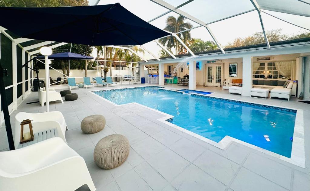 a swimming pool with an umbrella and white chairs at Home in Miami in Miami