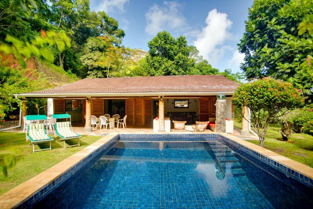 a house with a swimming pool in front of a house at Coté Sud - Unique Villa & Bungalows Intendance Road in Takamaka
