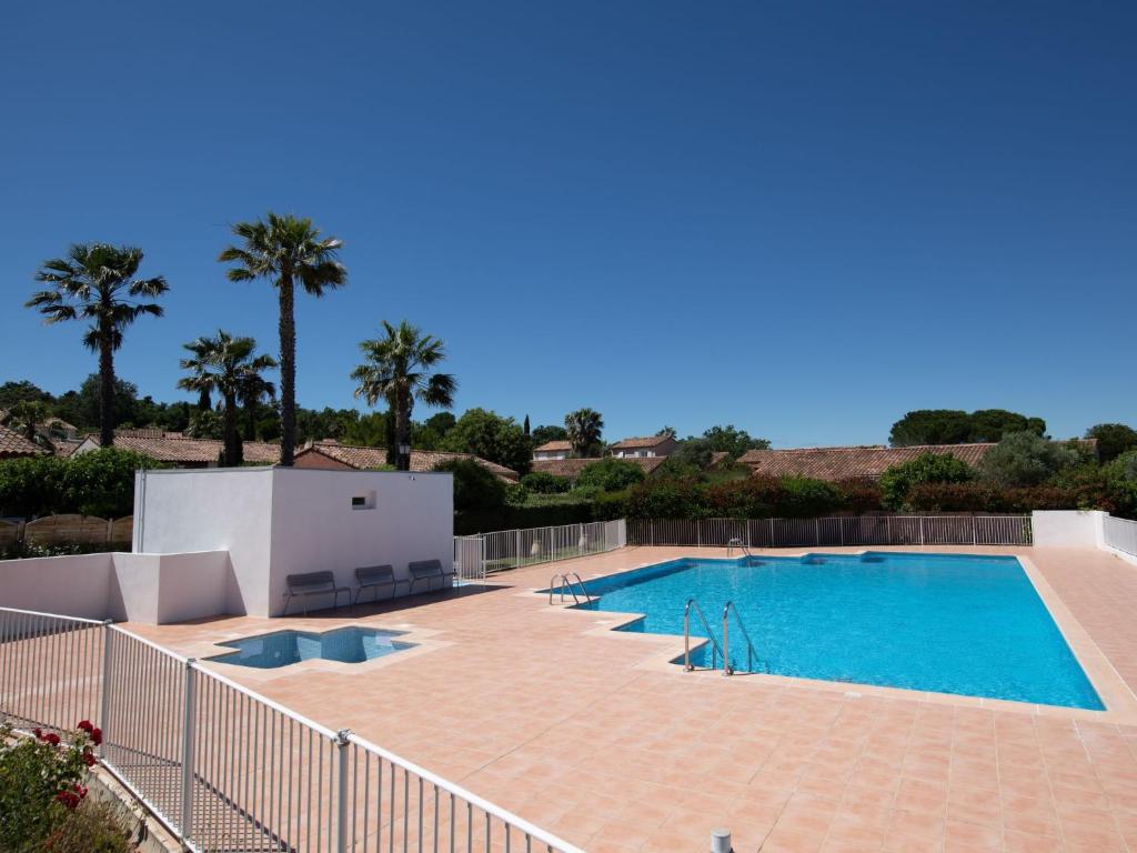 une grande piscine avec des palmiers en arrière-plan dans l'établissement Holiday Home Le Green Village-4 by Interhome, à Roquebrune-sur Argens