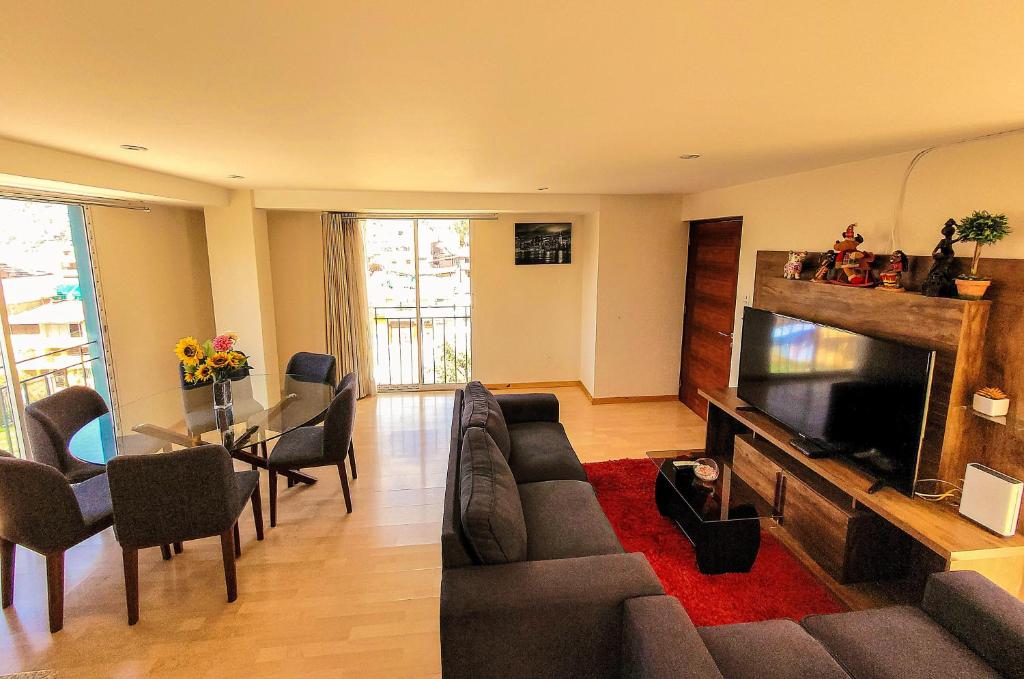 een woonkamer met een bank en een flatscreen-tv bij Fiflos Apartament in Cuzco