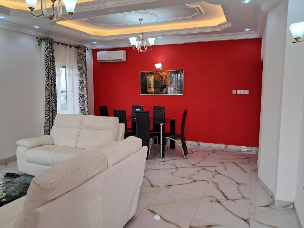 ein Wohnzimmer mit einem weißen Sofa und einer roten Wand in der Unterkunft Residence New Standing Douala CITE CHIRAC YASSA in Douala