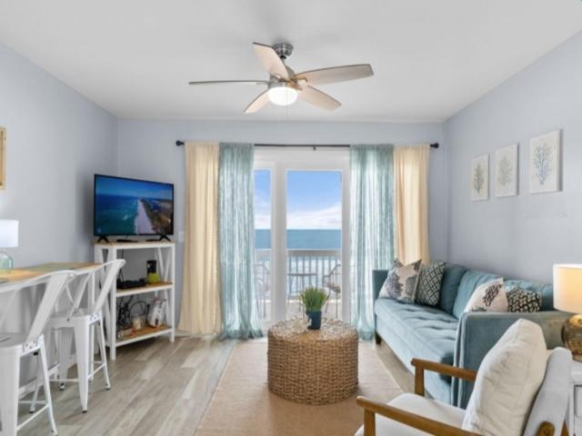 ein Wohnzimmer mit einem Sofa, einem Tisch und einem Fenster in der Unterkunft The Sea Willow - Beautiful ocean views! 2nd Floor - Oceanfront! condo in Carolina Beach