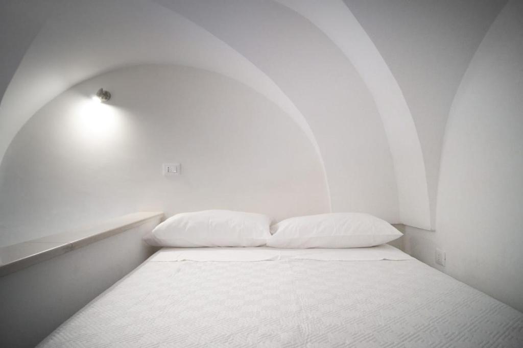 Cette chambre blanche dispose d'un lit avec deux oreillers. dans l'établissement Maremilia, à Ostuni