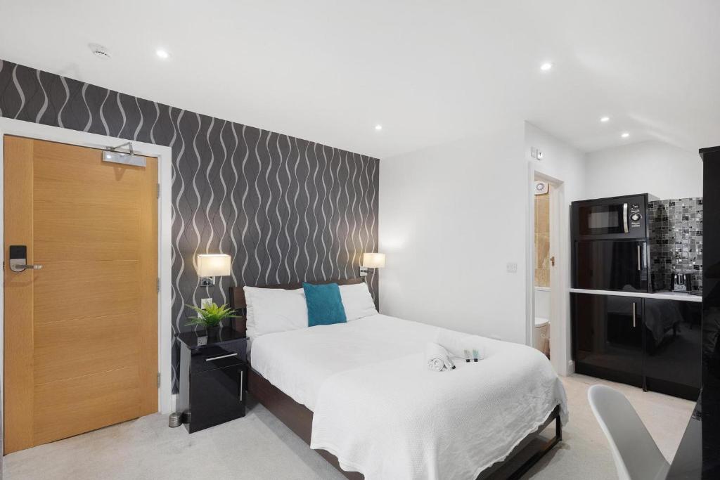 sypialnia z białym łóżkiem i ścianą w obiekcie Modern city centre studio apartment! w Oksfordzie