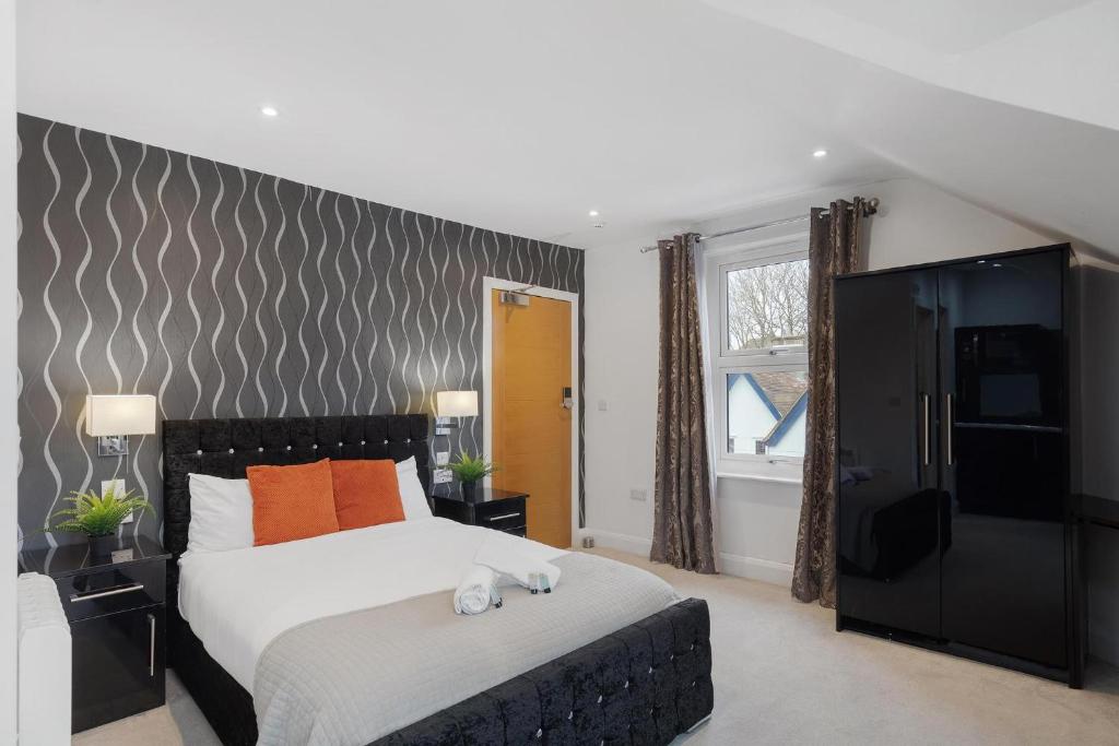 a bedroom with a large bed with orange pillows at Modern city centre studio apartment in Oxford