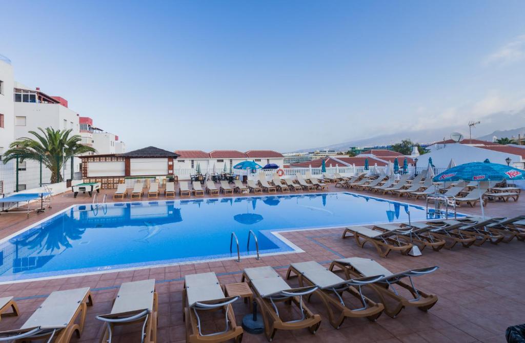 a large swimming pool with lounge chairs and tables at Apartamentos Tinerfe Garden in Adeje