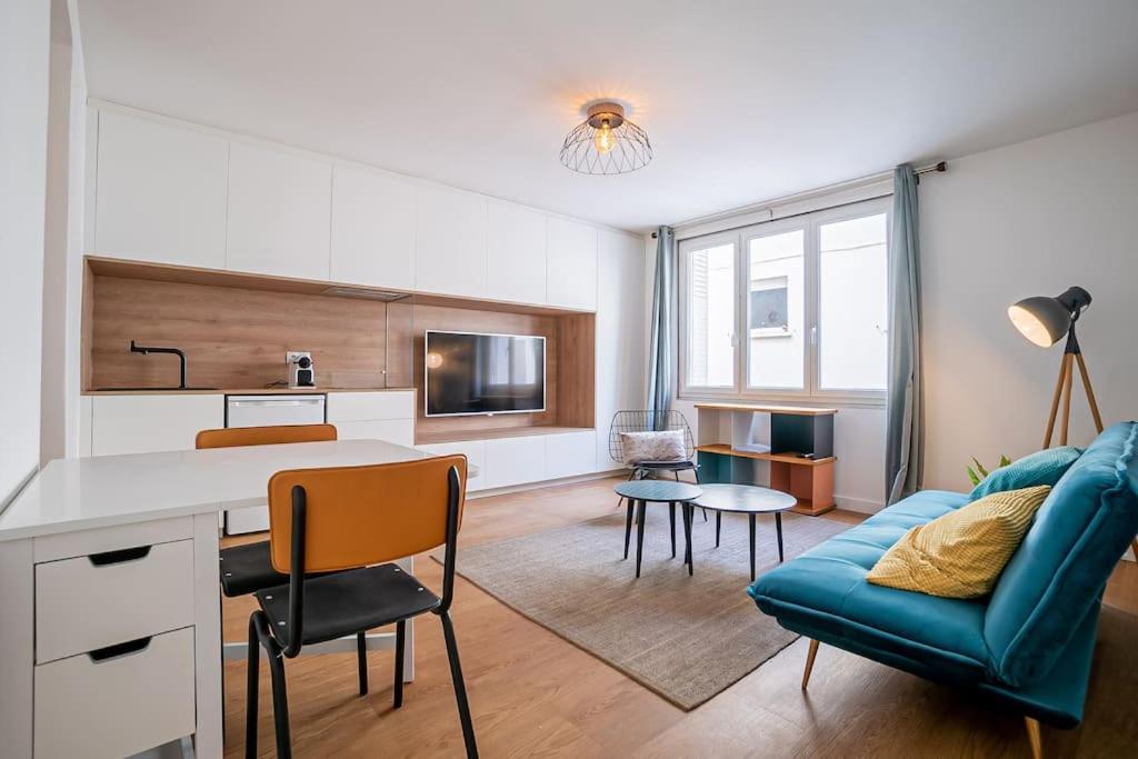 un salon avec un canapé bleu et une table dans l'établissement Le Contemporain, Charmant T1, Clim, Centre Ville, à Montpellier