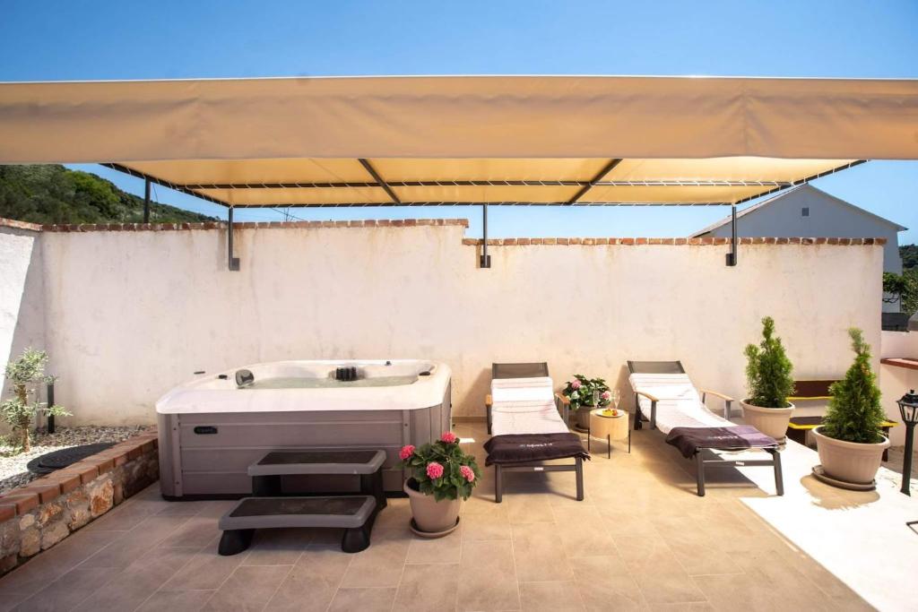 a hot tub sitting on a patio under an umbrella at House Olive tree in Mundanije