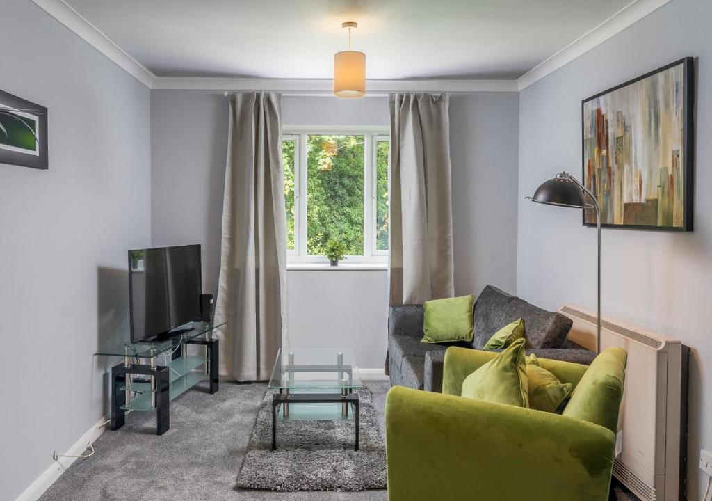 a living room with a green couch and a television at Crawley Thornhill 1 Bed Apartment near Gatwick Airport with Free Parking in Ifield