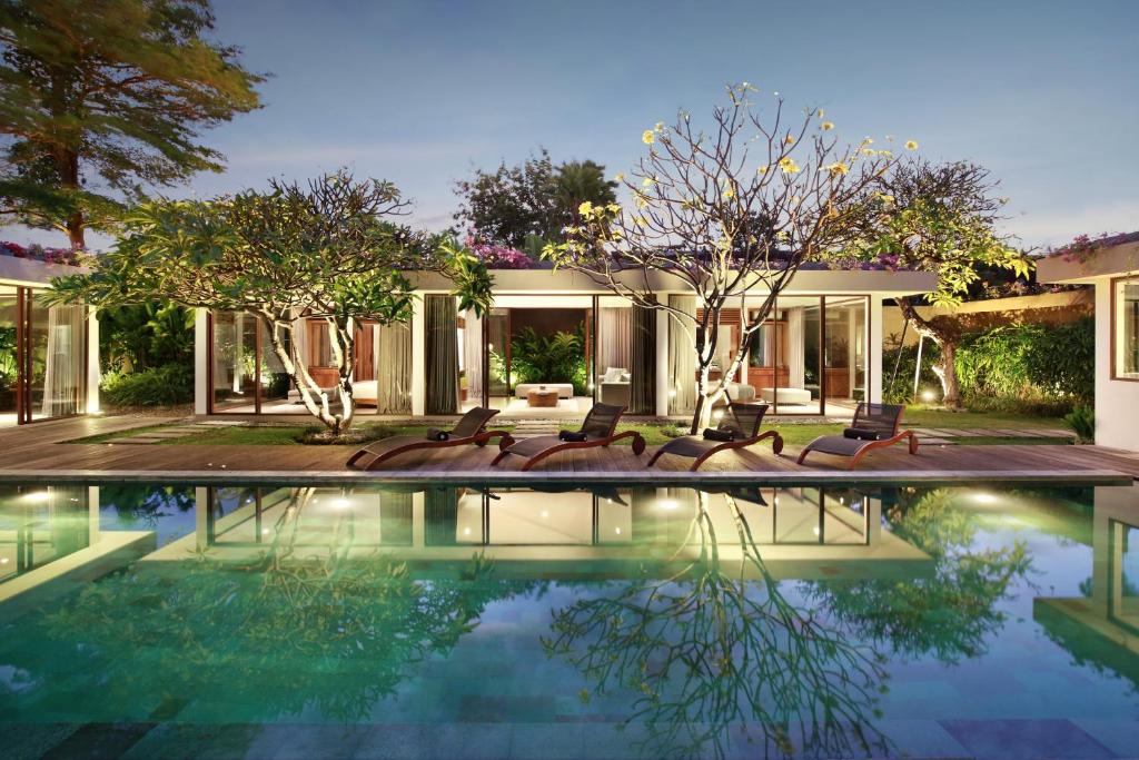 een huis met een zwembad met stoelen ervoor bij Ziva a Boutique Villa in Seminyak