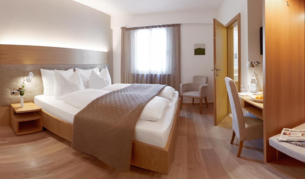 ein Hotelzimmer mit einem großen Bett und einem Schreibtisch in der Unterkunft Hotel Post Gries in Bozen