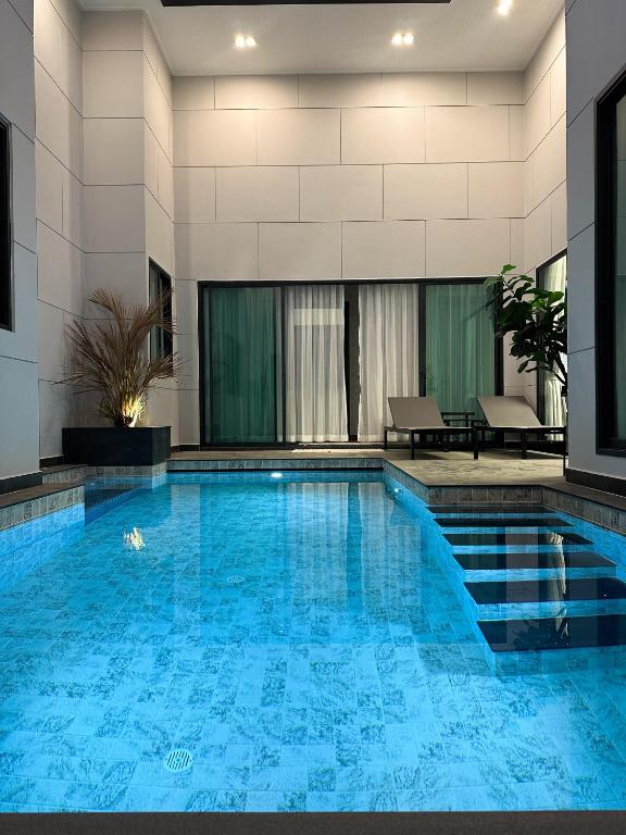 a swimming pool in a hotel with blue water at Chill Chill Pool Villa Pattaya in Nong Prue