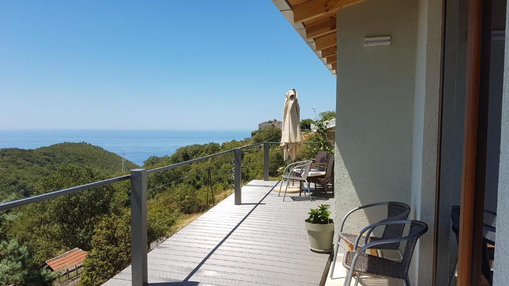 a balcony of a house with chairs and an umbrella at Adriatrek Bed & Breakfast in Petrovac na Moru