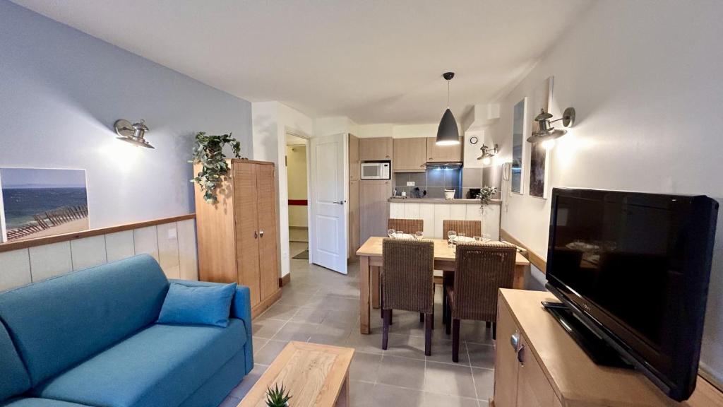 un salon avec un canapé bleu et une cuisine dans l'établissement Argousiers 14, à Fort-Mahon-Plage
