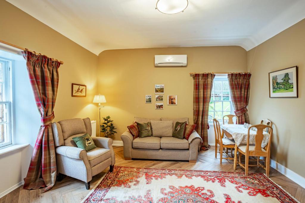 uma sala de estar com um sofá, cadeiras e uma mesa em Gardeners Cottage em Challoch