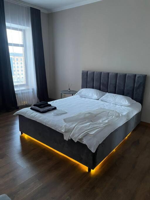 a bedroom with a large bed with lights on it at Элитные современные апартаменты с гостиничным сервисом in Karagandy