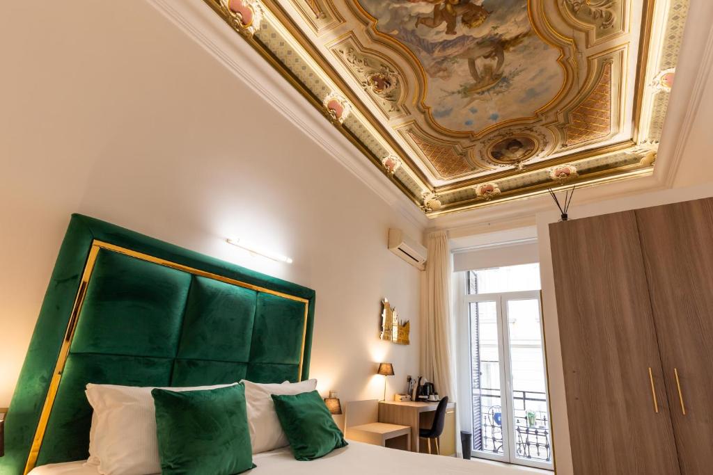 une chambre avec une grande tête de lit verte et un plafond dans l'établissement Cavour Luxury Rooms, à Rome