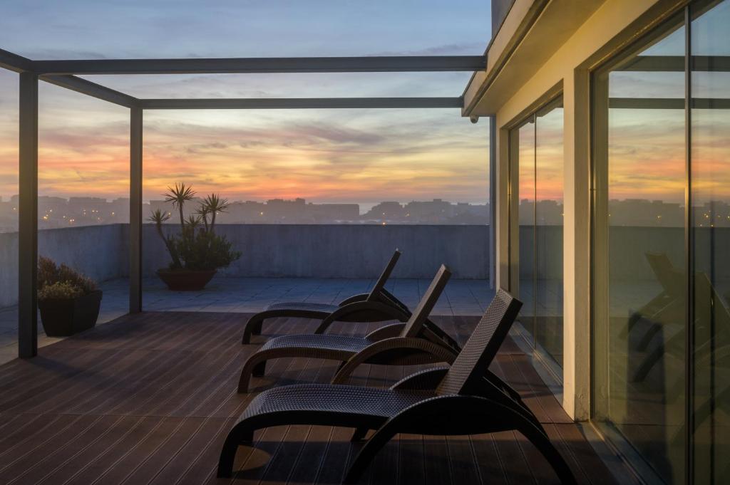 a row of chairs sitting on a deck with a sunset at Hotel Torre Mar in Póvoa de Varzim