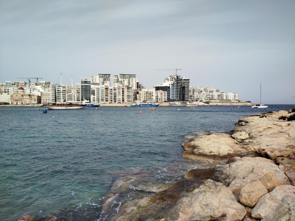 a view of a city from the water with rocks at Limestone Sun Suites in Sliema