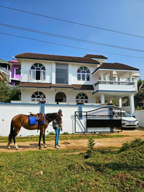 un hombre sosteniendo un caballo delante de una casa en Hestia Chalet 3BHK Villa en Ooty