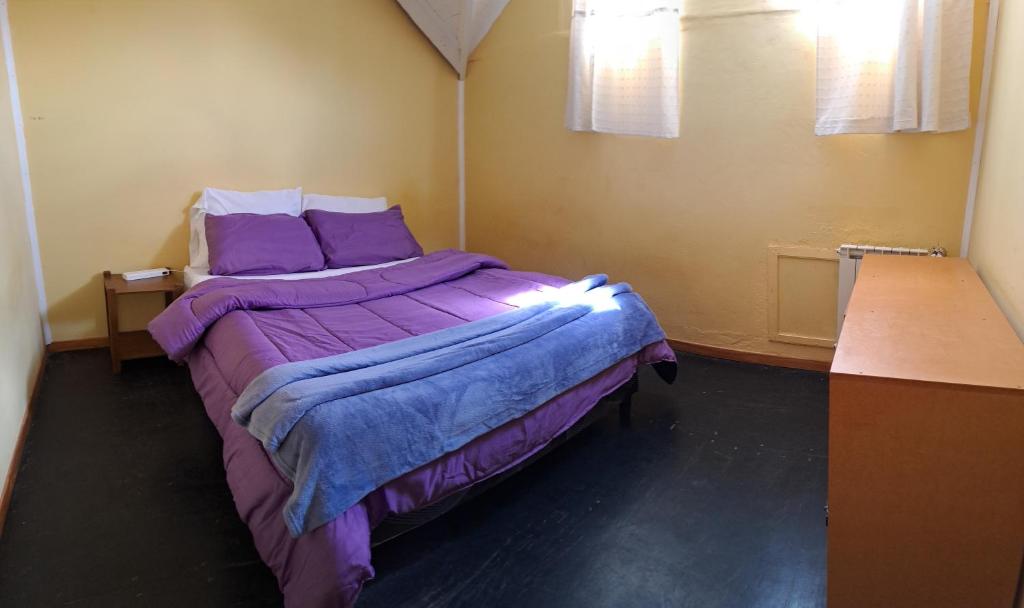 um quarto com uma cama roxa num quarto em Hostel Wenuy- em El Chaltén