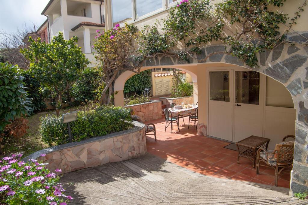 a patio with a table and chairs and flowers at Home Garden in Cala Gonone