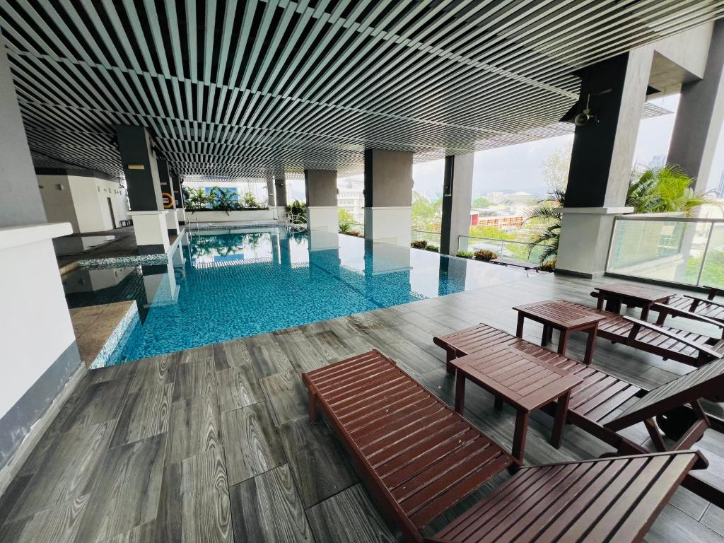 einen Pool mit Bänken und Tischen in einem Gebäude in der Unterkunft VUE Residences Klcc view ,2 min to HKL,Chowkit Monorail & MRT & BUS in Kuala Lumpur