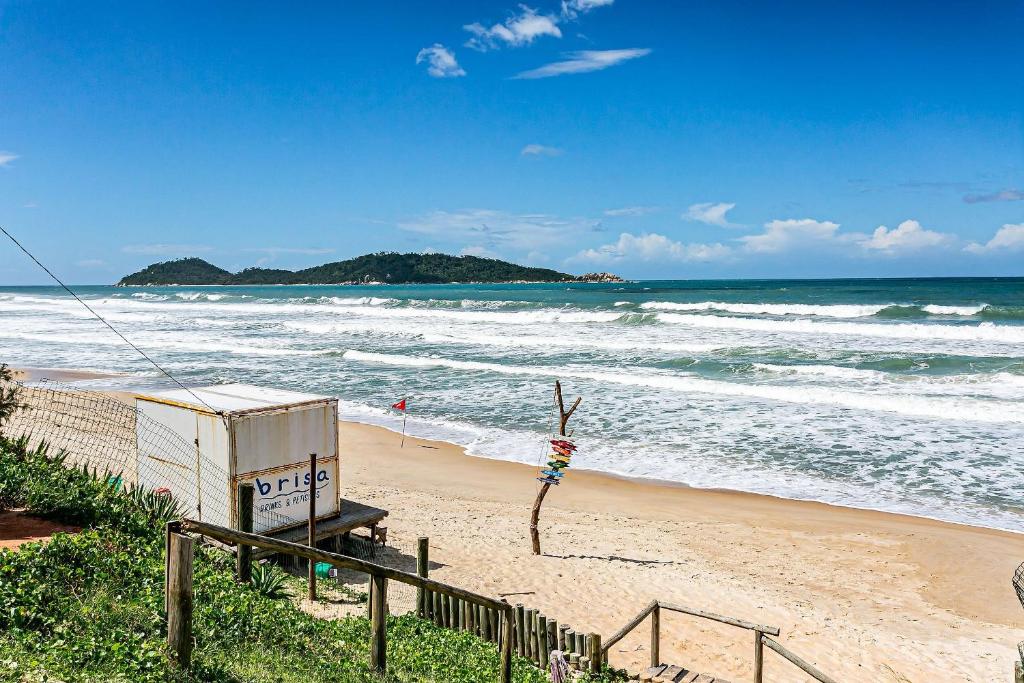 a sandy beach with a building and the ocean at Casa rústica com vista mar no Campeche TOCA151 in Florianópolis