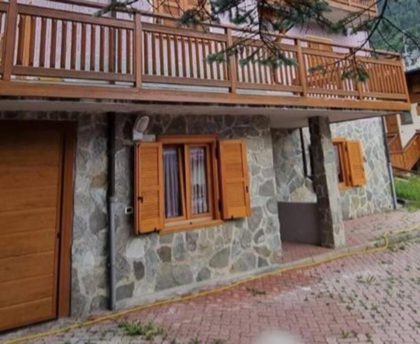 een stenen huis met een balkon en een houten deur bij Appartamento Aprica (SO) in San Pietro