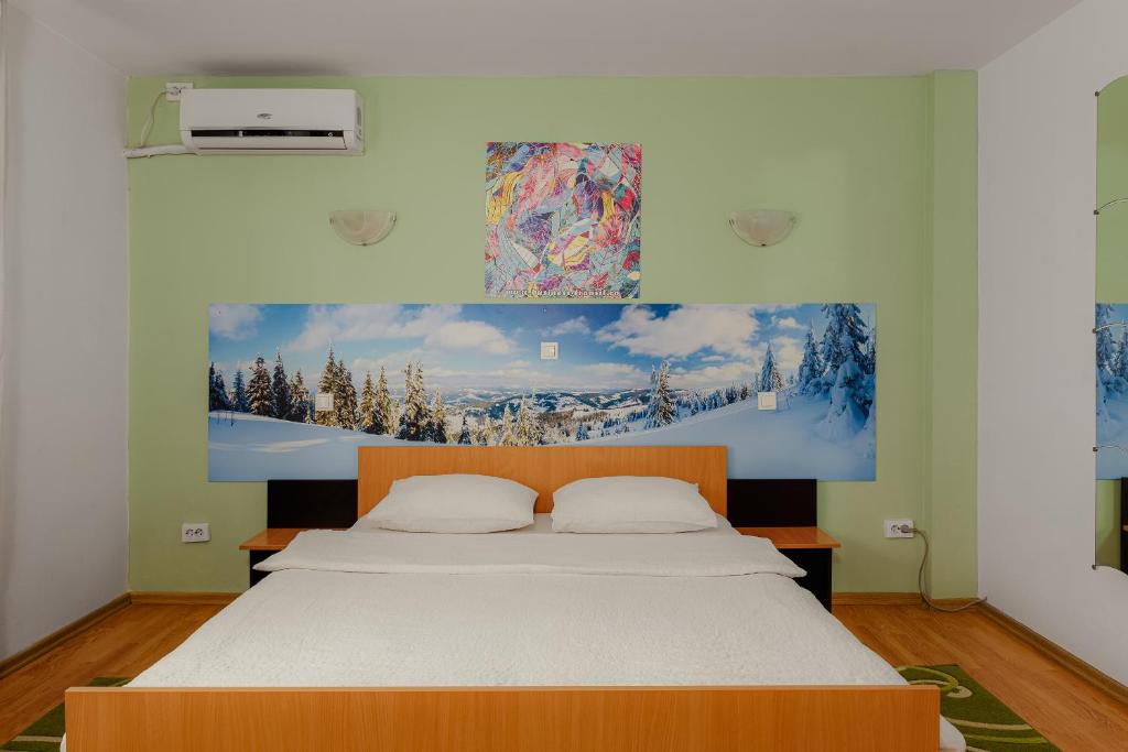 ein Schlafzimmer mit einem Bett mit einem Bild an der Wand in der Unterkunft Business Transit to Therme & Bucharest Airport in Săftica