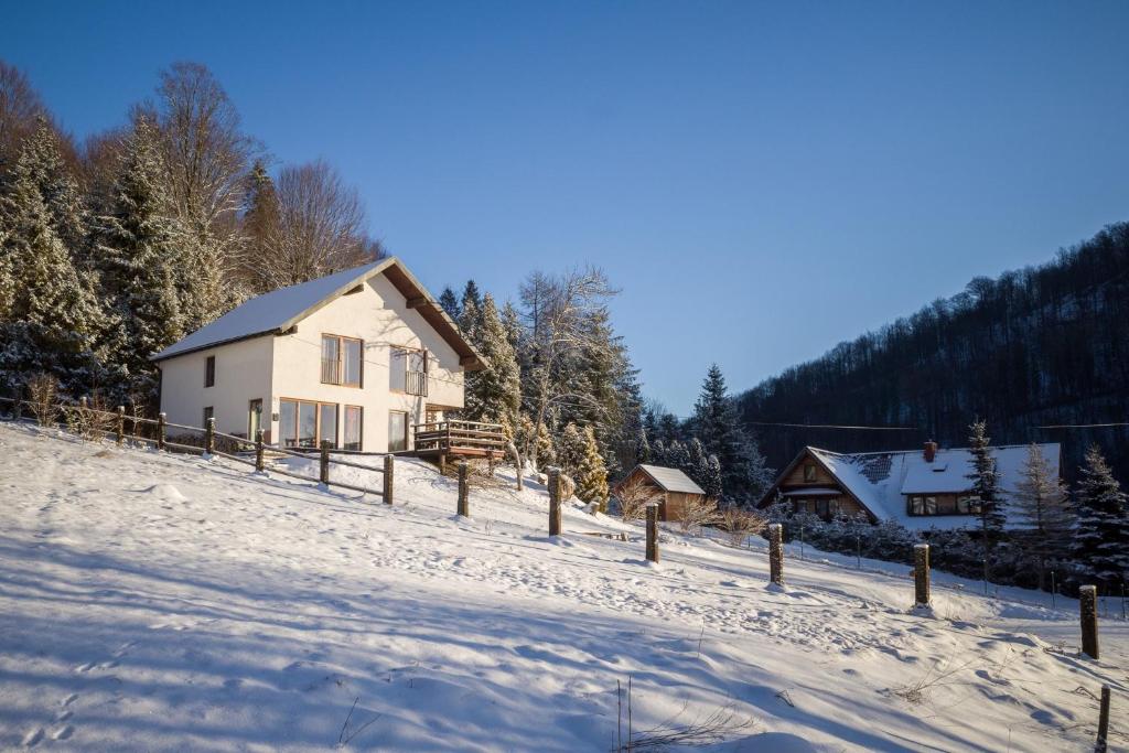 une maison dans la neige devant une maison dans l'établissement Dom na skraju parku, à Nasiczne