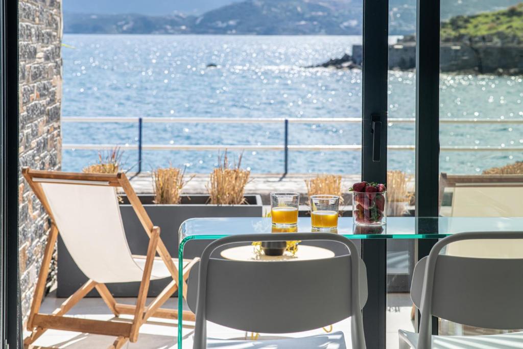 una mesa y sillas en un balcón con vistas al agua en Beachfront Salty Sea Luxury Suite 2 en Ágios Nikólaos