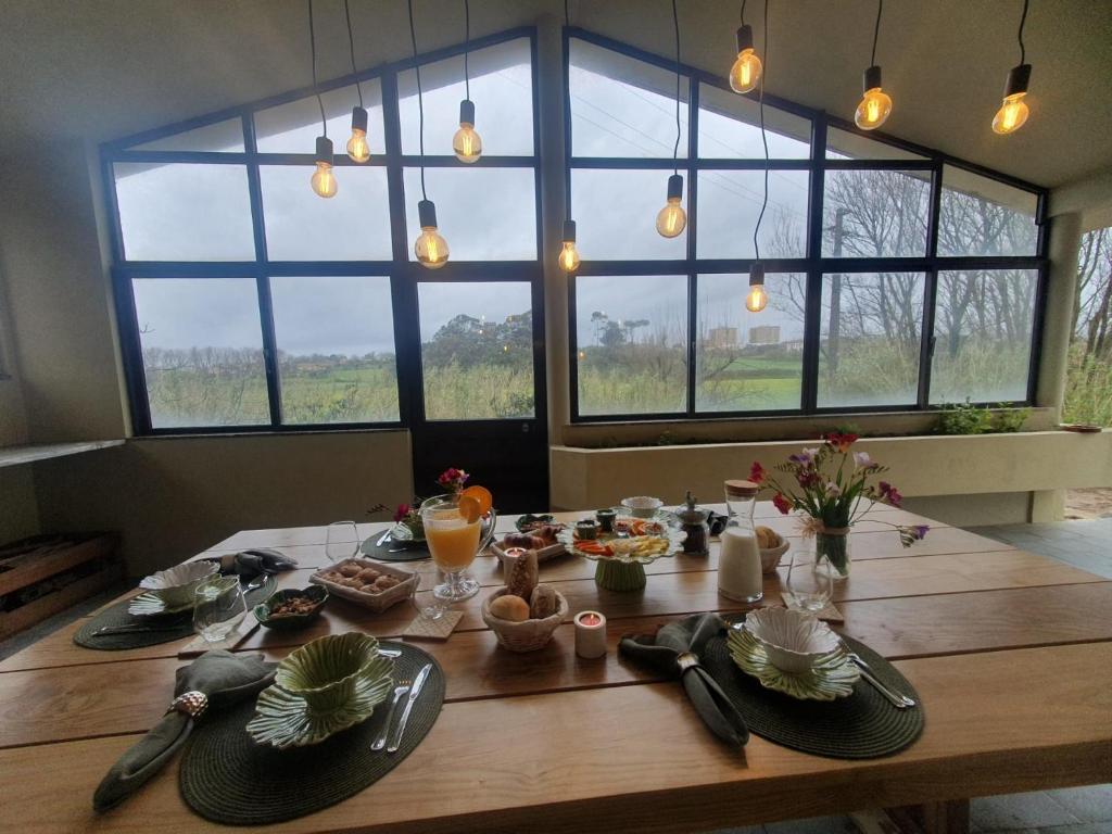 Azurara Guesthouse في Azurara: طاولة خشبية عليها طعام في غرفة بها نوافذ