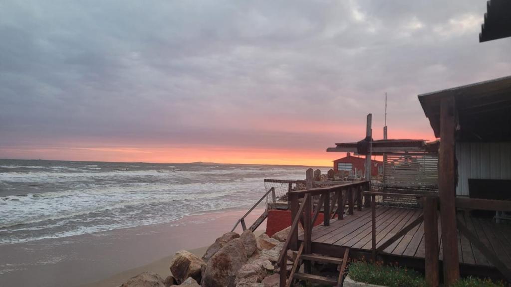 Amanecer en aguas dulces في أغواس دولسيس: شاطئ به مبنى و المحيط وقت الغروب