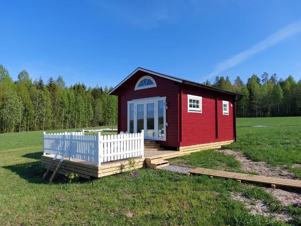 ein rotes Haus mit einem weißen Zaun auf einem Feld in der Unterkunft Gästehaus Lilla-Viken in Stöde