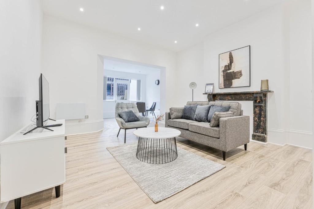 ein Wohnzimmer mit einem Sofa, einem TV und einem Tisch in der Unterkunft Spacious 1 Bedroom Apartment in Cheltenham Centre 