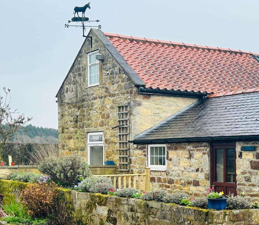 a stone house with a cat on the roof at Twattleton Cottage Kilburn Yorkshire - Beautiful views in York