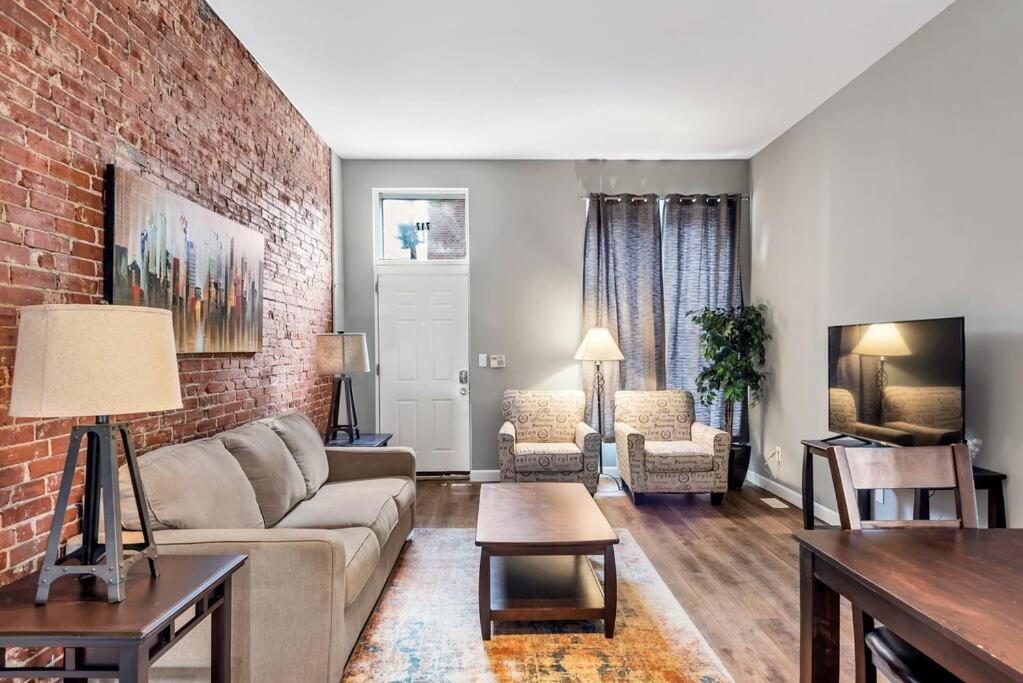a living room with a couch and a brick wall at Settle into Soulard 4 Beds 2 full baths in Soulard
