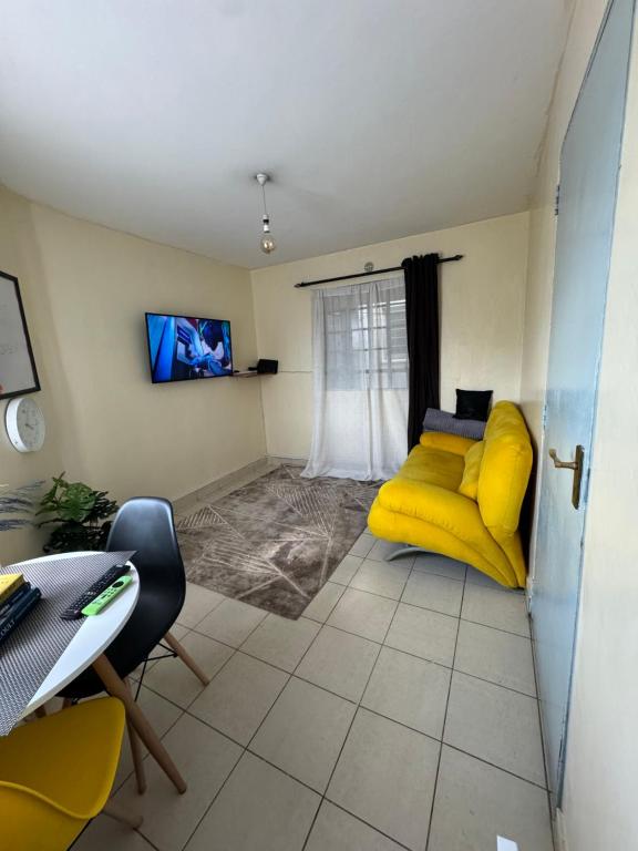 a living room with a yellow couch and a tv at Ample Residence in Nairobi