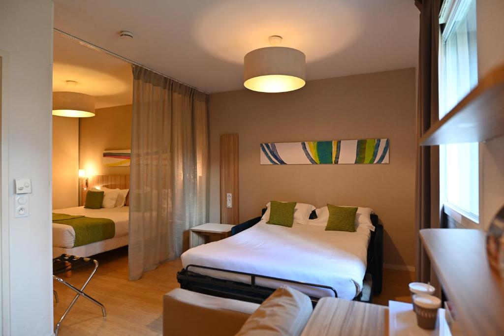 a hotel room with two beds and a couch at Appart hôtel Q7 Lodge Lyon 7 in Lyon