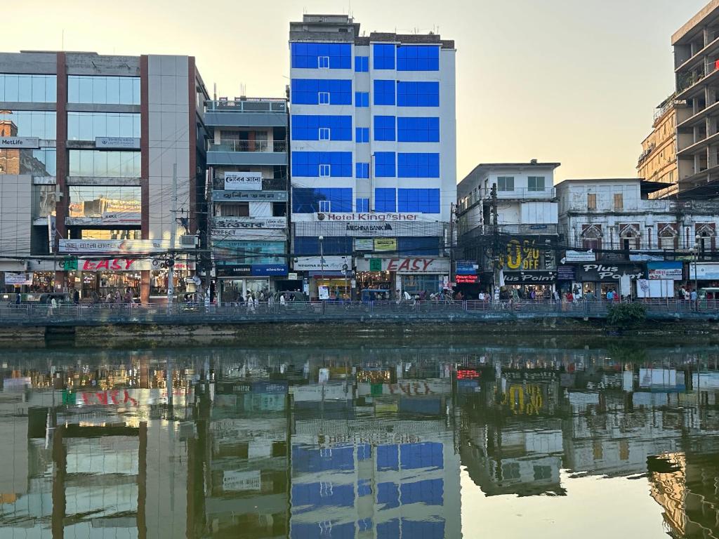 eine Stadt mit hohen Gebäuden neben einem Wasserkörper in der Unterkunft Hotel Kingfisher - Barishal in Barishal